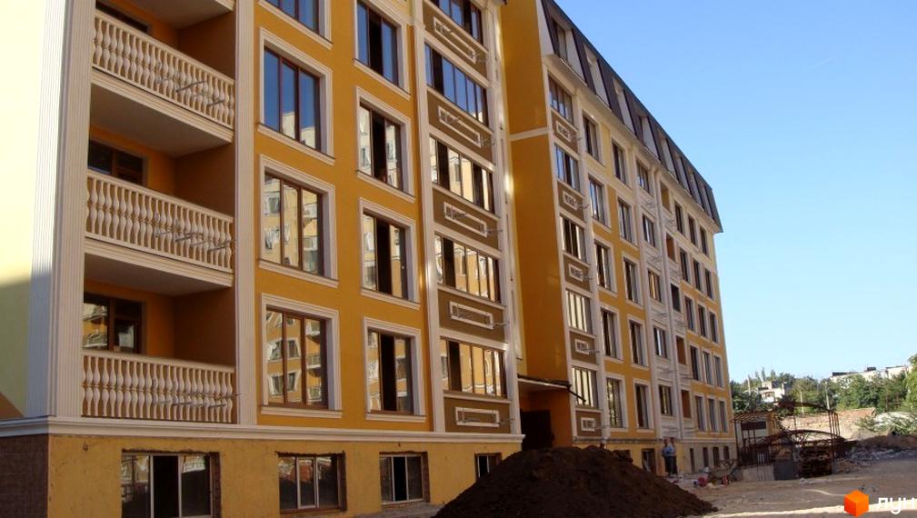 Зовнішній вигляд житлового комплексу Академмістечко з балконами та великими вікнами. Прибудинкова територія з будівельними матеріалами.