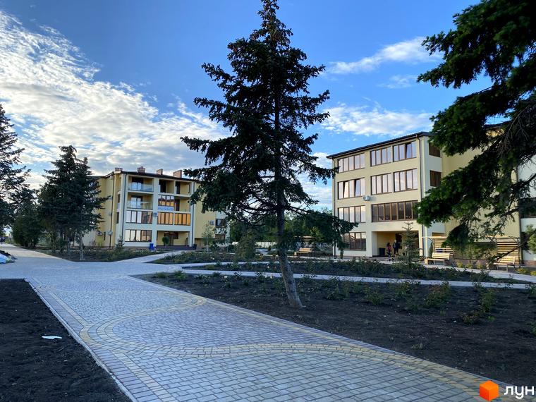 Житловий комплекс GRAND FAMILY APARTMENTS: світлі будинки з великими вікнами та балконами, оточені доріжками та зеленими насадженнями.