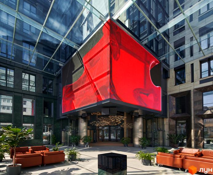 Зображення внутрішнього двору Житлового комплексу Chicago Central House з великим червоним екраном. Вигляд на будівлю та лаунж-зону з диванами.