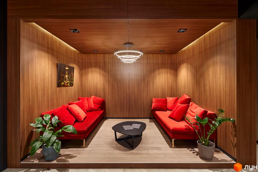 Затишна зона відпочинку в ЖК Chicago Central House. Дерев'яне оздоблення стін та стелі, м'які дивани з червоними подушками, декоративні рослини.