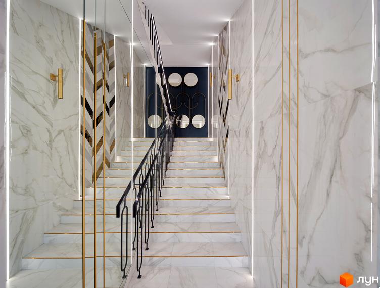 Сходи в ЖК Chicago Central House з білим мармуром, золотими лініями та чорною кованою огорожею. Стіни прикрашені підсвічуванням та декоративними елементами.