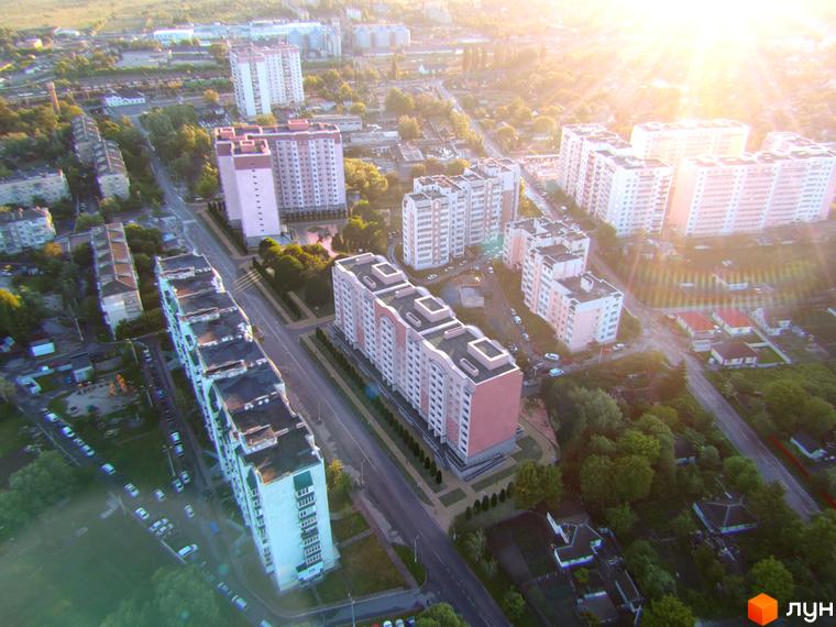 Житловий комплекс Світанок: висотні будинки з рожевими та білими фасадами, огороджена територія з деревами та парковкою.