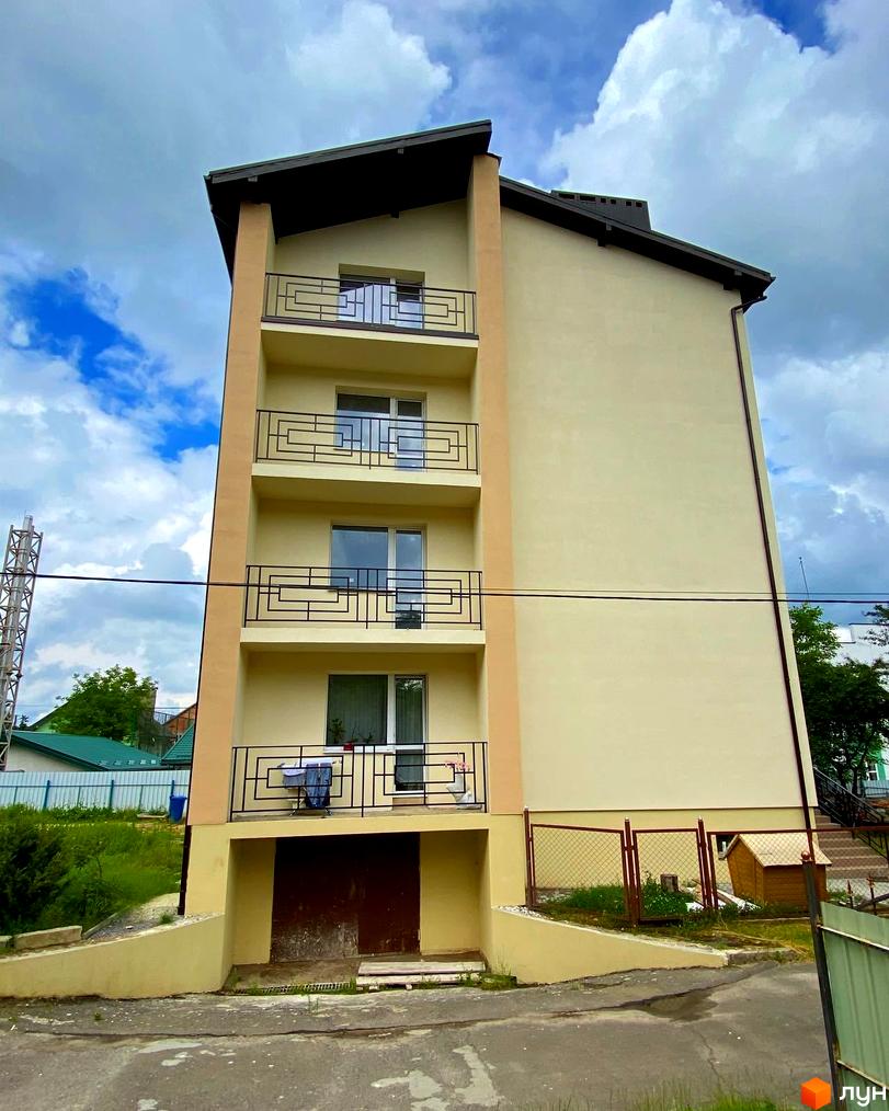 Будівельний проєкт на вул. Спортова, 12 має світлий фасад, балкони з чорними поручнями та прибудинкову територію з парканом та дитячим будиночком.