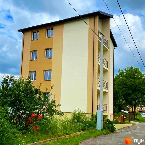 Зовнішній вигляд триповерхового будинку на вул. Спортова, 12, з фасадом у двох кольорах та балконами. На прибудинковій території видно зелені насадження та елементи благоустрою.