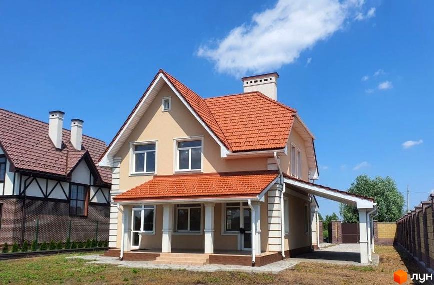 Фото двоповерхового будинку з терасою та червоним дахом у Котеджному містечку Осокорки. Навколо будинку зелений газон та доглянута територія.