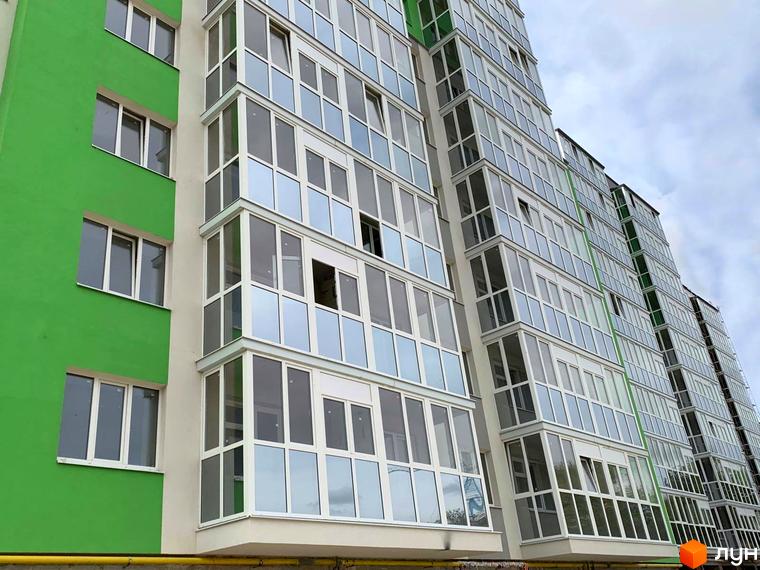 Фасад житлового комплексу Оград з зеленими та білими елементами, багато вікон та балконів.
