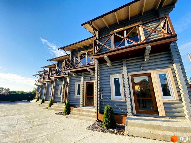 Зовнішній вигляд таунхаусів LEVEL з дерев'яними балконами та сірими стінами. Поруч розташований вимощений двір та зелені насадження.