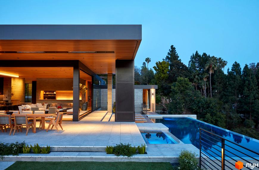 Котеджне містечко Ula.community з басейном та зоною відпочинку на фоні зелених дерев. Сучасний дизайн екстер'єру з дерев'яними елементами та великими вікнами.