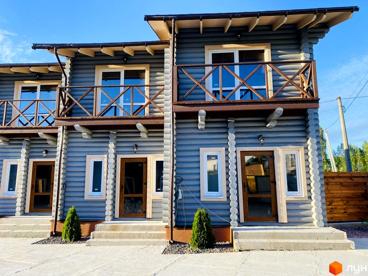 Двоповерхові таунхауси LEVEL з дерев'яним оздобленням та балконами. Поруч доглянуті зелені насадження та бетонна доріжка.