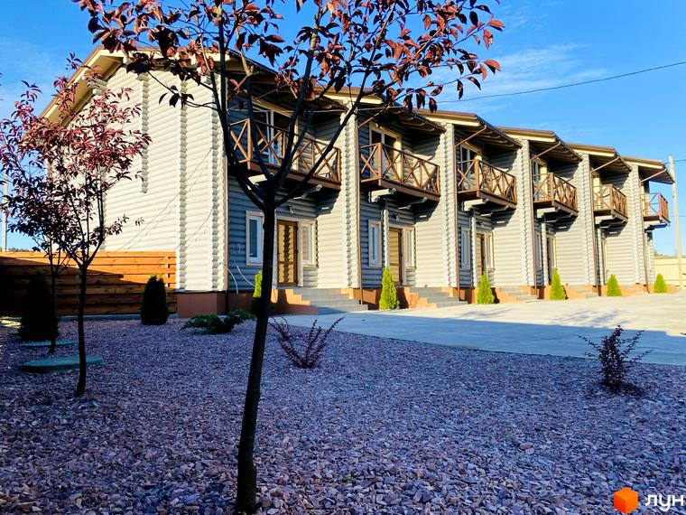 Таунхауси LEVEL, двоповерхові будинки з балконами, розташовані на території з бруківкою та деревами.