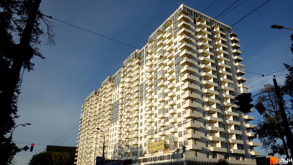 Житловий комплекс Перлина Нивок з сучасним фасадом та балконами. Прибудинкова територія з зеленими насадженнями та доріжками.