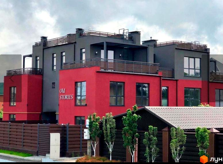 Таунхауси Old Stories з червоними та сірими фасадами, вікнами та балконами. Навколо огороджена територія з деревами та парканом.