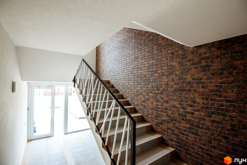 Сходи у клубному будинку Craft з цегляною стіною та великими вікнами. Сучасний дизайн інтер'єру під'їзду.