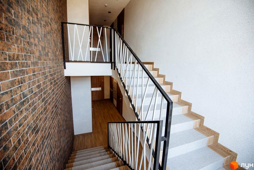 Клубний будинок Craft. Сучасний під'їзд з цегляною стіною, сходами та дверима.
