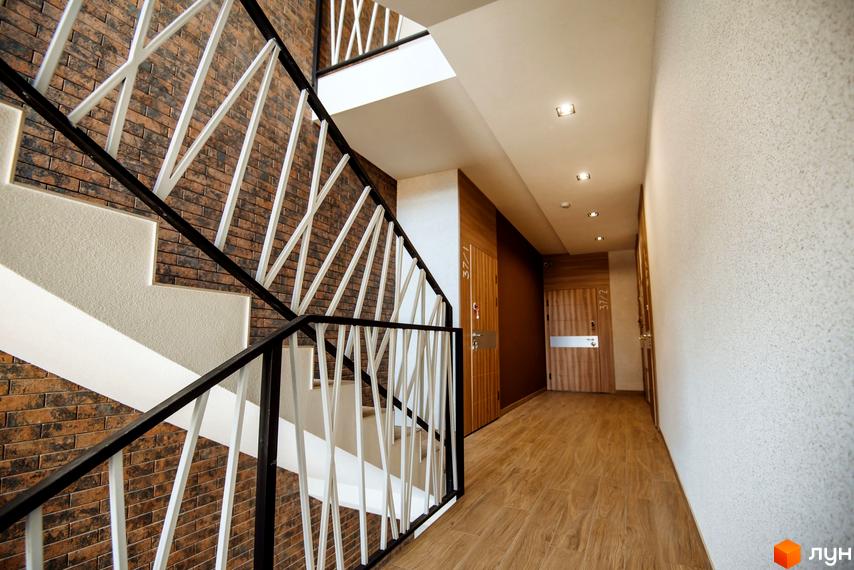 Сходи та коридор у житловому комплексі Craft. Сучасний дизайн з цегляною кладкою та дерев'яними елементами.
