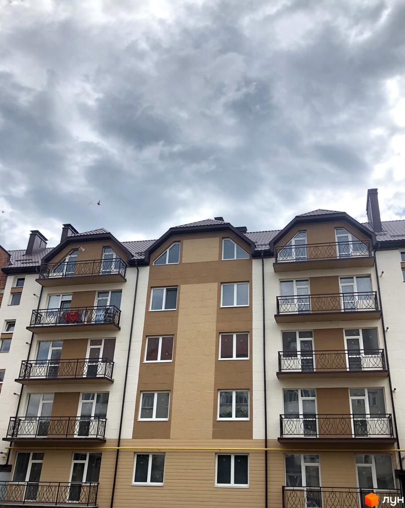 Фасад житлового комплексу Котляревського з балконами та вікнами під сірим небом. Будинок має коричнево-бежеву обробку та темний дах.