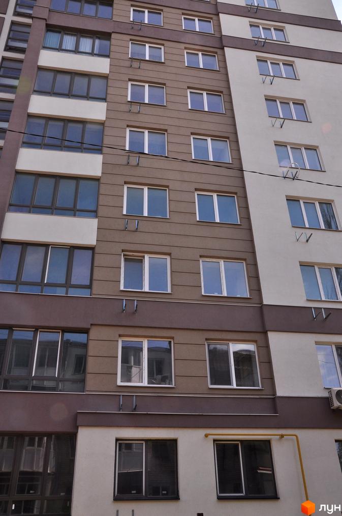 Фасад житлового комплексу Мирний з великою кількістю вікон та балконів. Будинок має коричнево-білу кольорову гаму.