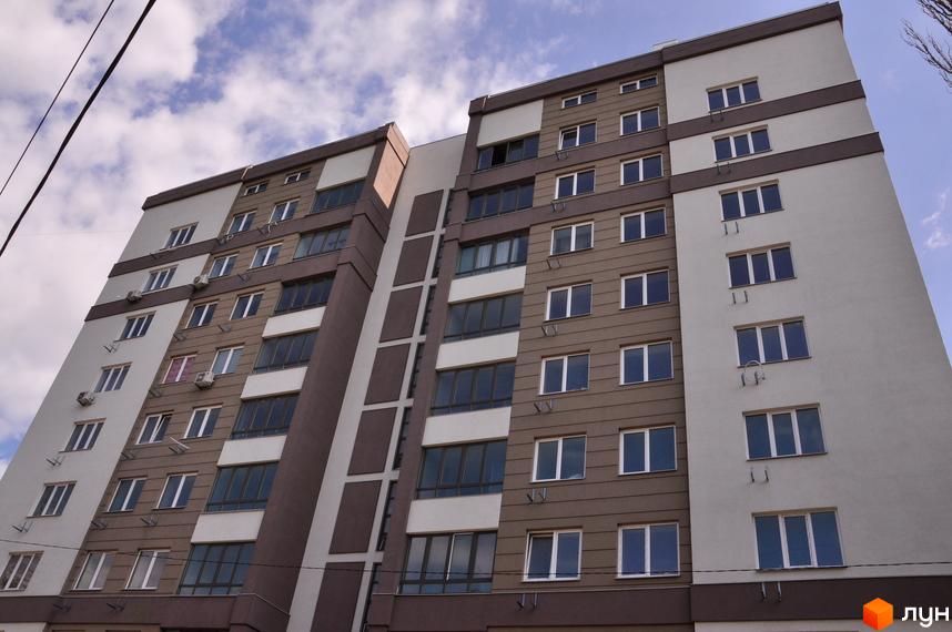 Зовнішній вигляд багатоповерхового будинку ЖК Мирний з коричневими та білими фасадами. Вікна розташовані рівномірно по всій висоті будівлі.