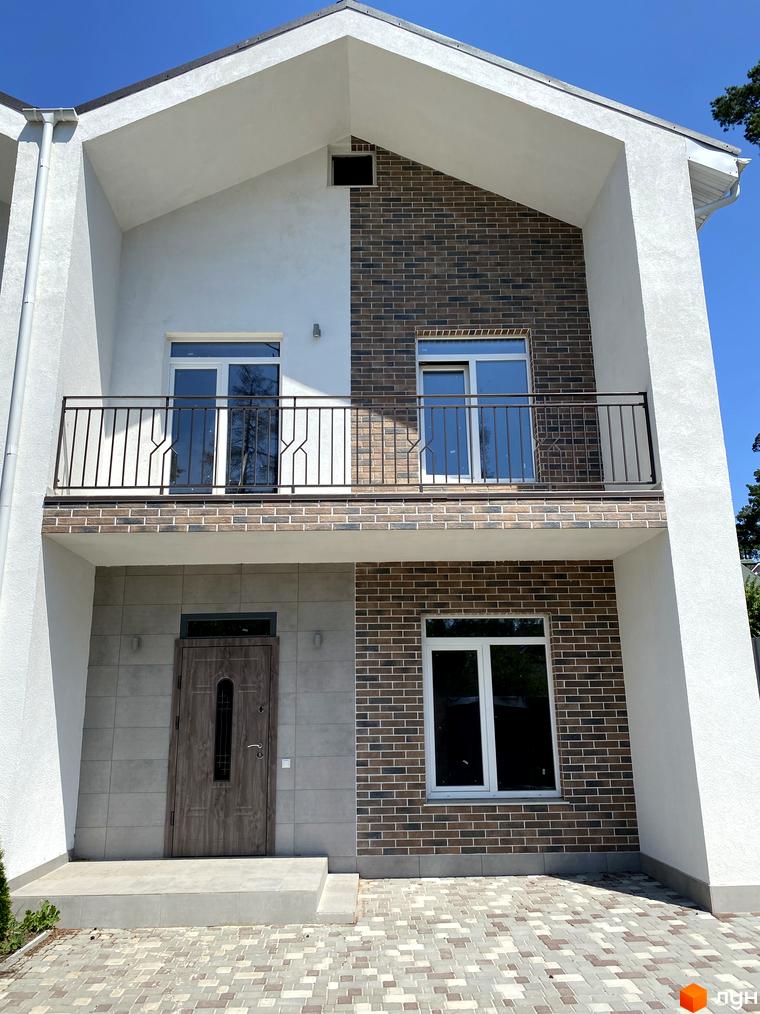 Дуплекс „На Києво-Мироцькій“: фасад будинку з цегляним та білим оздобленням, балкон та вхідна група. Прибудинкова територія викладена плиткою.