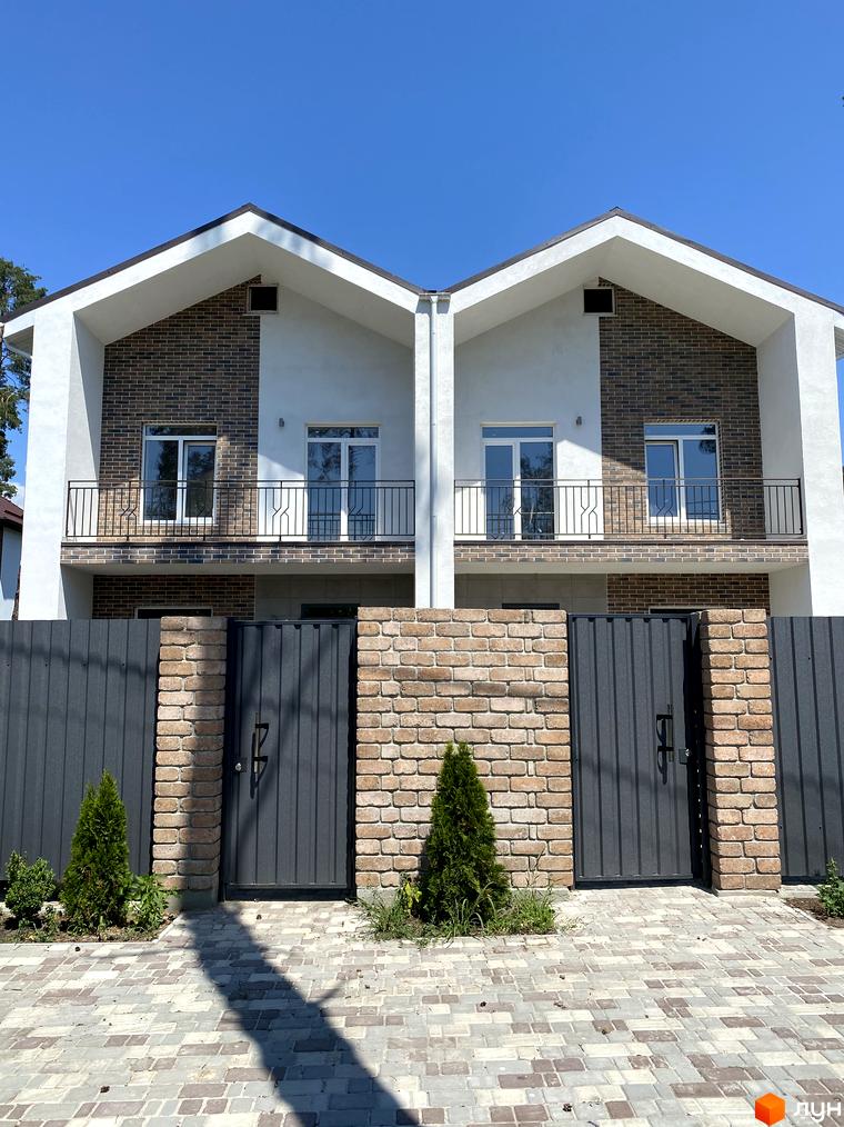 Дуплекс „На Києво-Мироцькій“: фасад з цегляними та білими елементами, балконами та парканом з воротами.