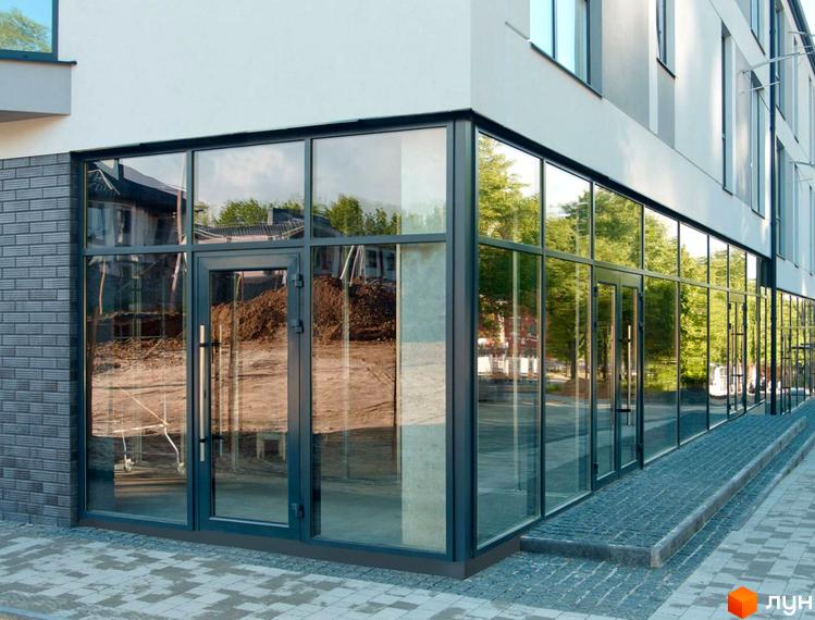 Клубний будинок Craft з великими панорамними вікнами та вхідною групою, що виходить на вимощену бруківкою територію.