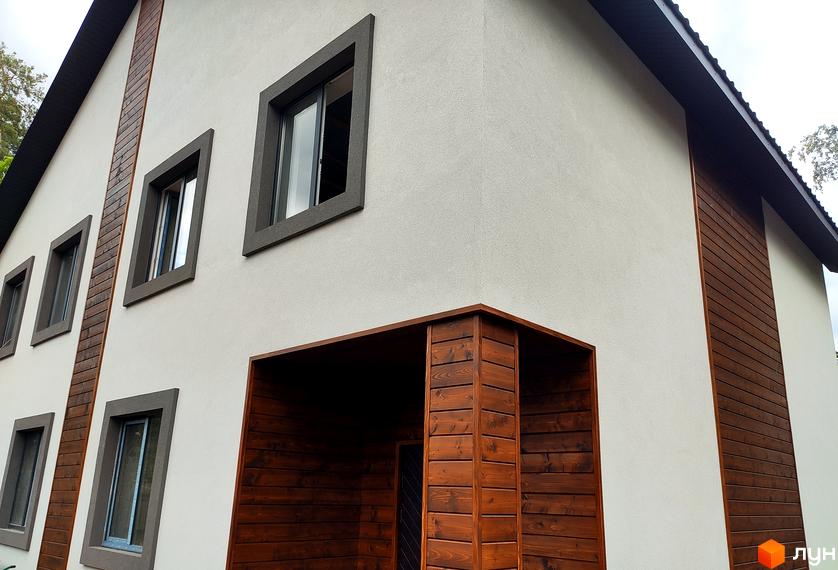 Зовнішній вигляд новобудови на вул. Пушкінська, 12з з білою штукатуркою та дерев'яними елементами, вікнами з темними рамами.