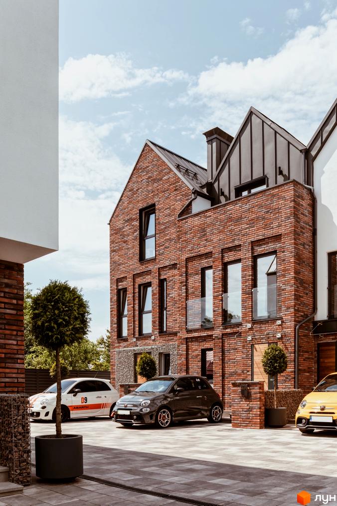 Котеджне містечко КМ Wunder Haus з цегляними фасадами та автомобілями на прибудинковій території. Зовнішній вигляд будинків та парковка біля новобудови.