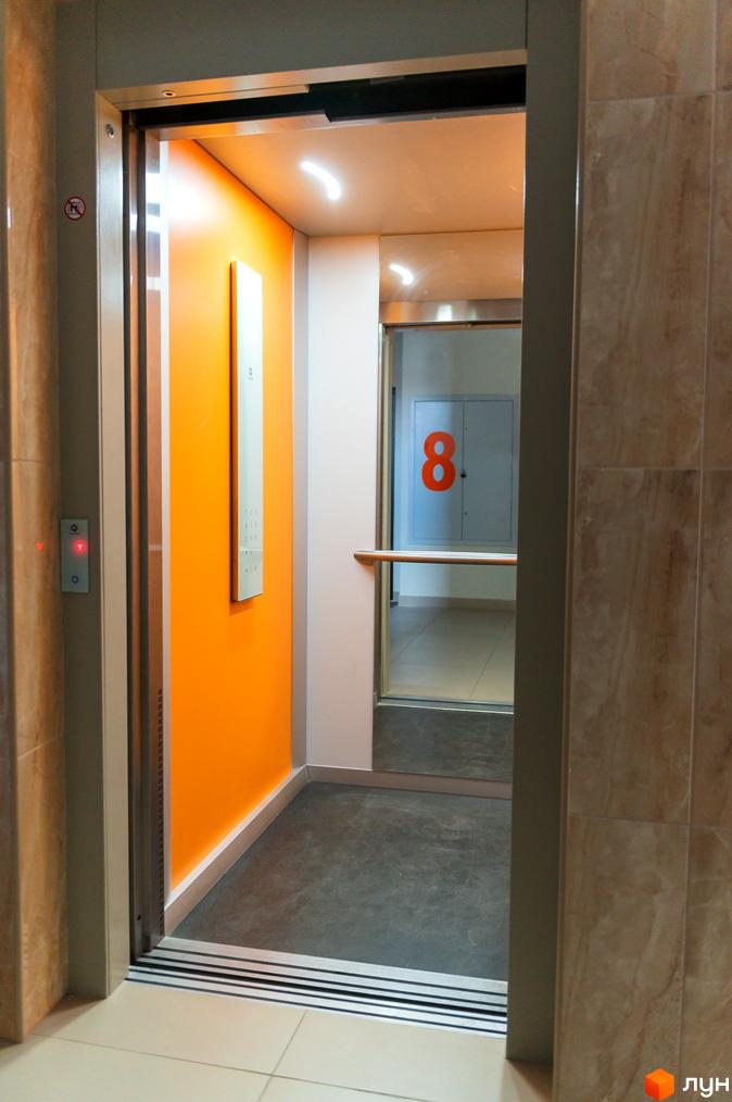Житловий комплекс Orange Park має ліфт з яскравою помаранчевою стіною та зручною панеллю управління. Швидкий доступ до всіх поверхів.