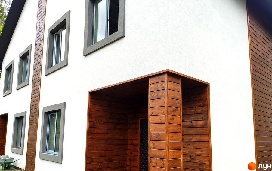 Сучасний житловий комплекс на вул. Пушкінська, 12з з білим фасадом та дерев'яними елементами. Зовнішній вигляд новобудови з вікнами та вхідною групою.