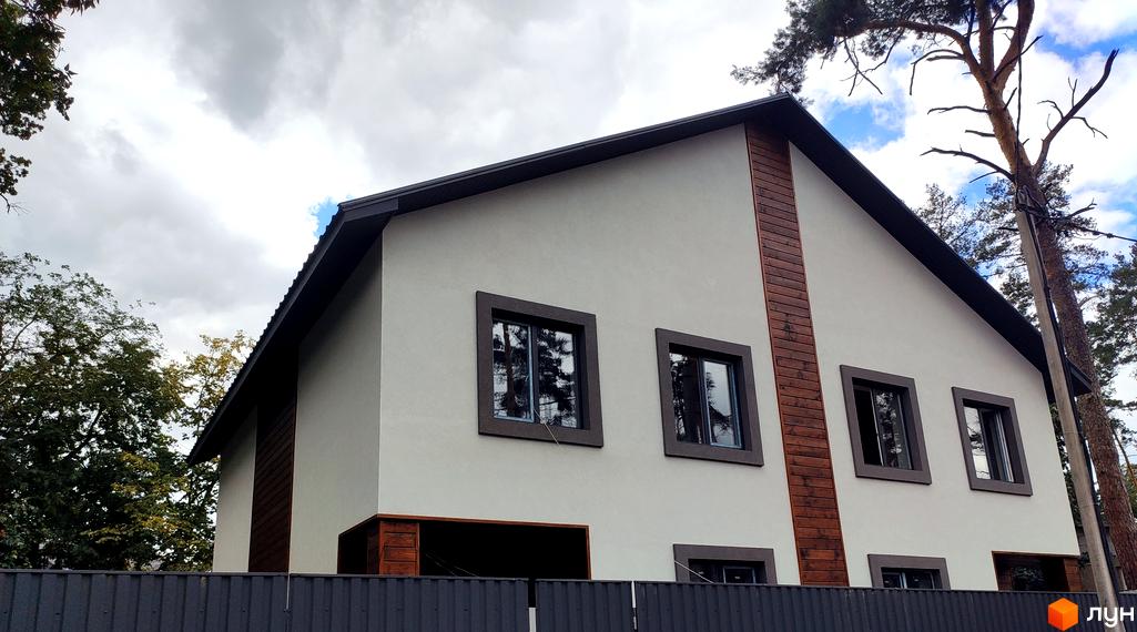 Будинок з білою штукатуркою та дерев'яними вставками на вул. Пушкінська, 12з. Навколо будинку дерева та сірий паркан.