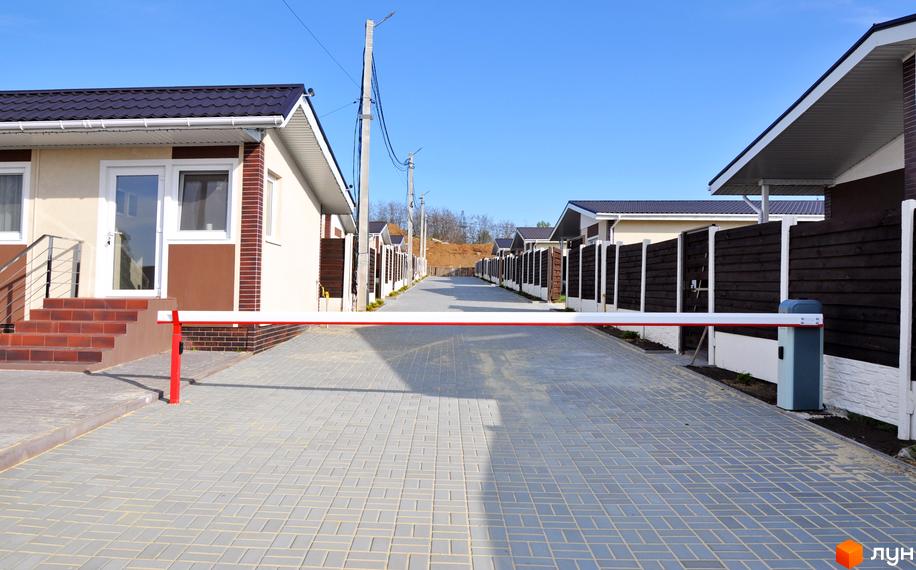 Котеджне містечко КМ Данилівський: огороджена територія з бруківкою та парканами, сучасні будинки з темними дахами.