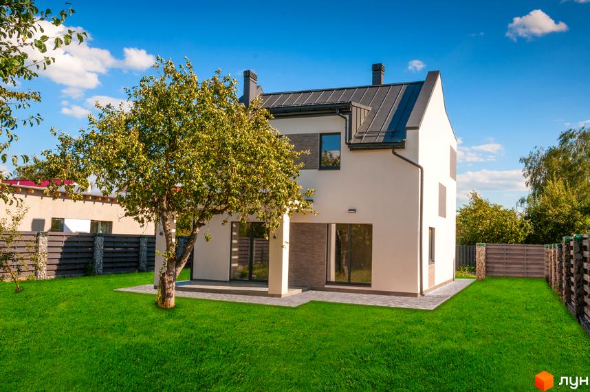 Білий двоповерховий будинок з темним дахом та скляними дверима, перед будинком зелена галявина та велике дерево, навколо будинку паркан.