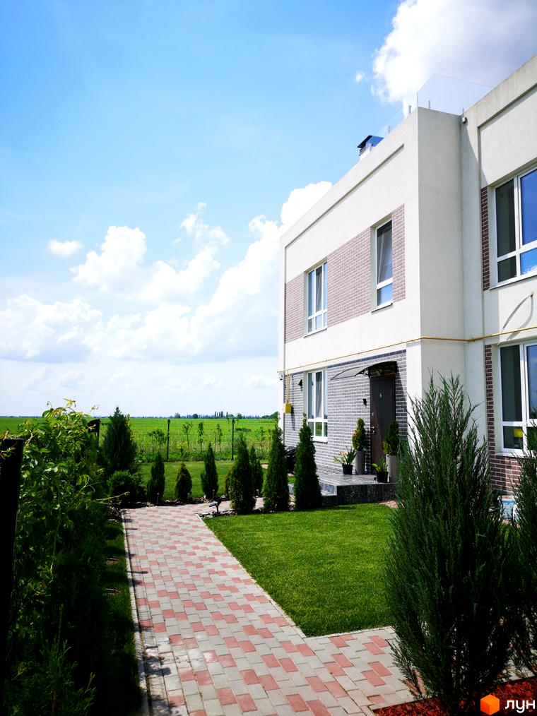 Зовнішній вигляд будинку Country Townhouse з цегляним фасадом та великими вікнами. Прибудинкова територія з доглянутим газоном та доріжкою з плитки.
