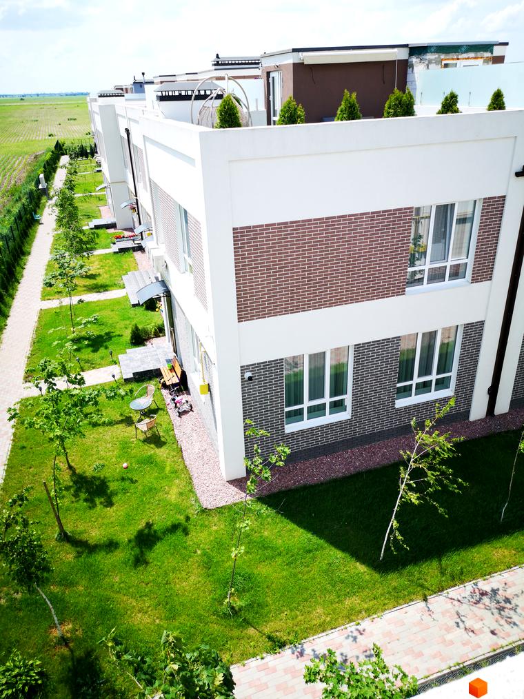 Зовнішній вигляд будинку Country Townhouse з цегляним фасадом та великими вікнами. Прибудинкова територія з газоном та деревами.