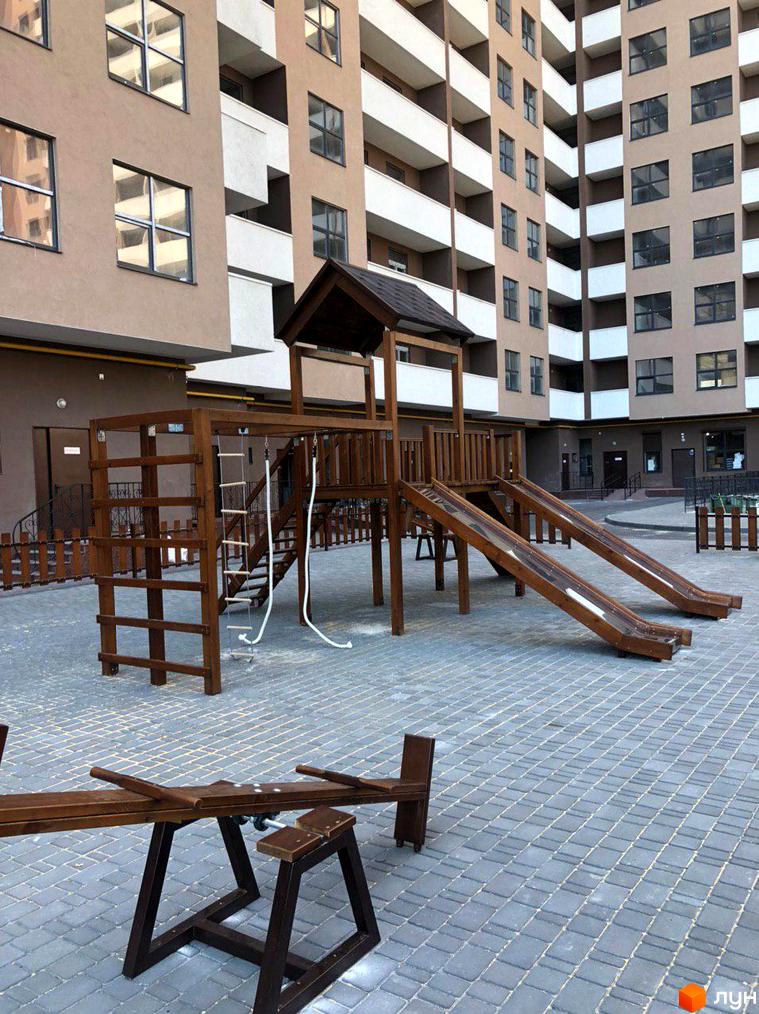 Житловий комплекс Баку: фасади будівель з великою кількістю вікон та балконів. На прибудинковій території дитячий майданчик з дерев'яними гірками та гойдалками.