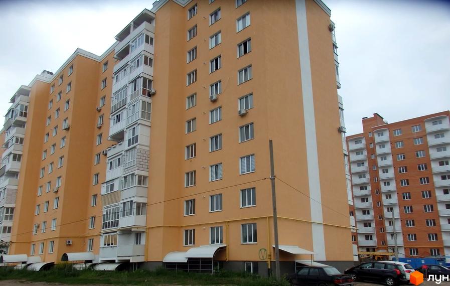Зображення багатоповерхового будинку по вул. Олександра Мацієвського, 8. На передньому плані прибудинкова територія з газоном та автомобілями.