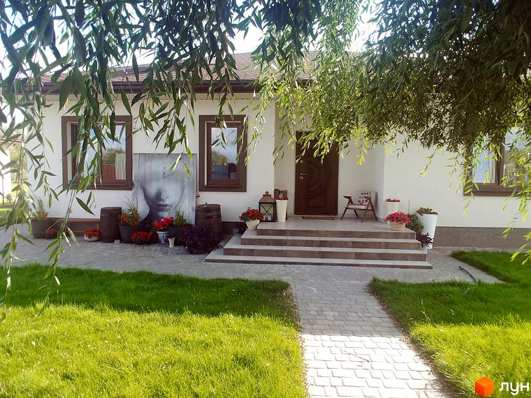 КМ Маєток: затишний будинок з вишуканим фасадом та доглянутою прибудинковою територією з газоном та квітковими композиціями. Ідеальне місце для комфортного життя.