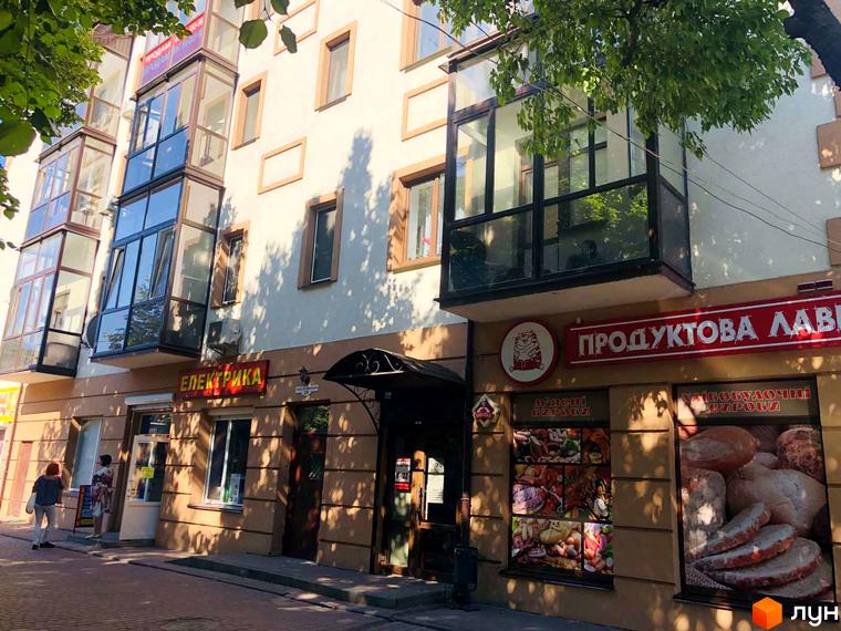 Фасад житлового комплексу на вулиці Петра Могили, 28, з балконами та комерційними приміщеннями на першому поверсі. Зовнішній вигляд будівлі з вітринами магазинів.