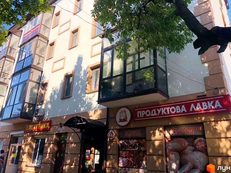 Зовнішній вигляд житлового комплексу на вулиці Петра Могили, 28. Фасад будівлі оздоблений світлою штукатуркою та коричневими елементами, з великими вікнами та скляними балконами.