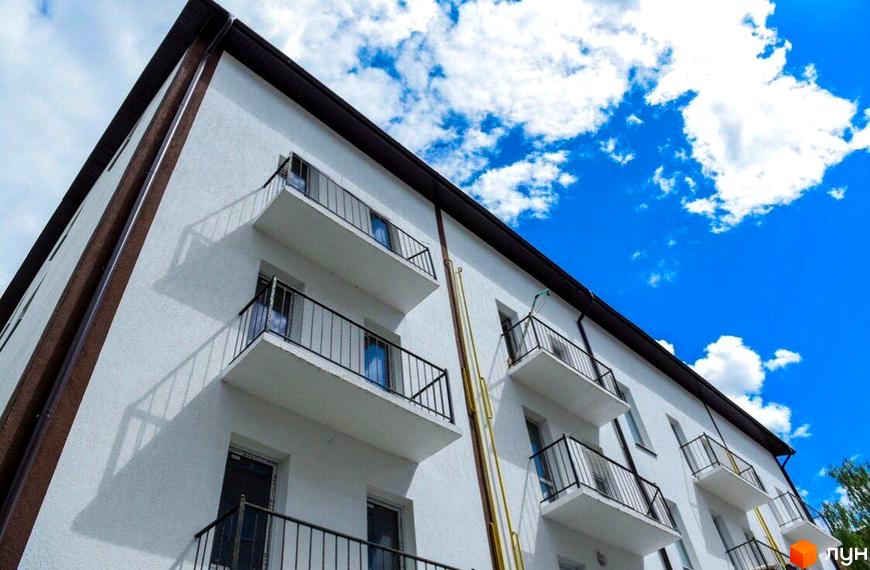 Зовнішній вигляд новобудови за адресою пров. Мирогощанський, 35, з балконами та вікнами на тлі блакитного неба з хмарами.