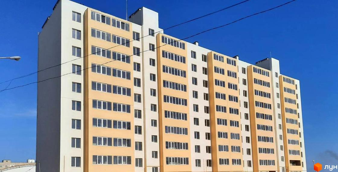 Зовнішній вигляд багатоповерхового житлового комплексу Морський (Южне) з жовто-білими фасадами та численними вікнами на тлі блакитного неба.