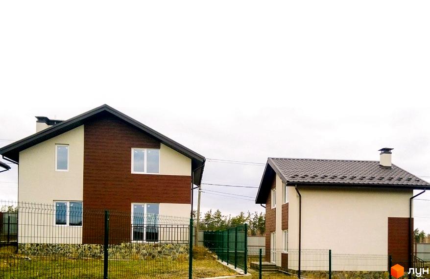 Котеджне містечко КМ Нова Конча-Заспа. Зовнішній вигляд двоповерхових будинків з коричневим фасадом та білими стінами, огороджена територія.