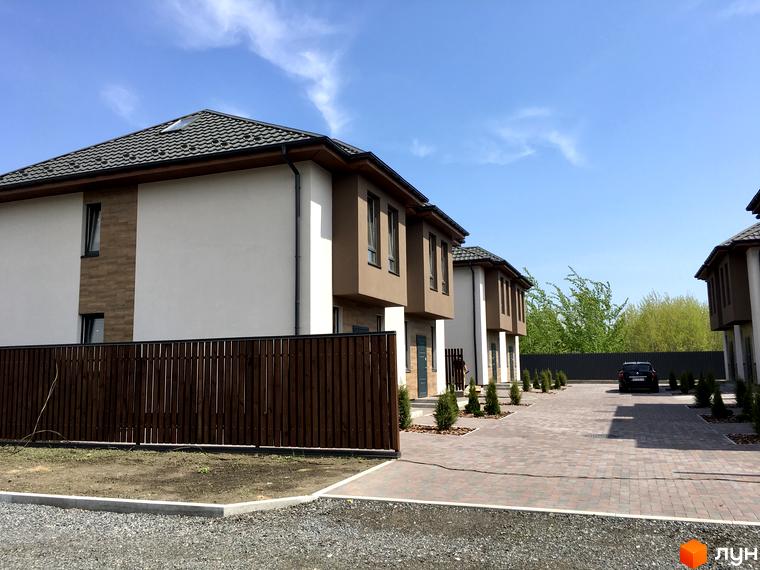 Дуплекси „На Вишгородській“ – двоповерхові будинки з коричневими та білими фасадами, огороджені дерев'яним парканом. Прибудинкова територія вимощена бруківкою, з доглянутими зеленими насадженнями.