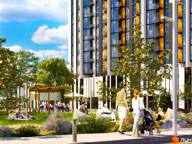 Житловий комплекс Central Bucha з яскравим фасадом та зеленою прибудинковою територією, де відпочивають люди.