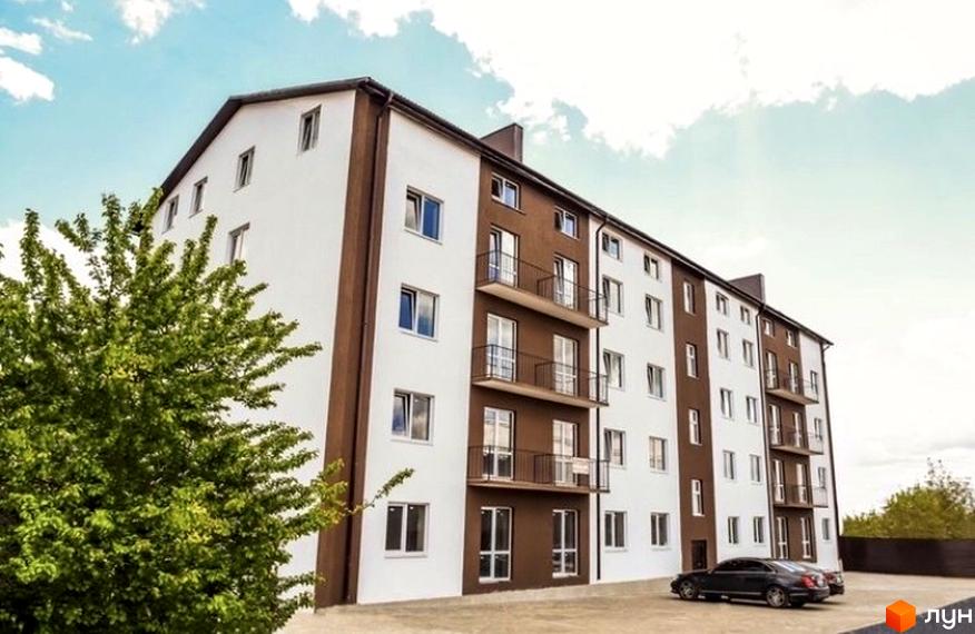 Зовнішній вигляд новобудови на вул. Кирила і Мефодія, 27, з біло-коричневим фасадом та балконами. Прибудинкова територія з паркуванням та зеленню.