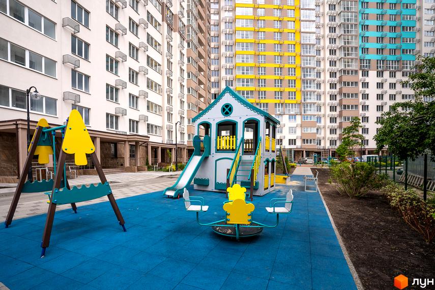 Дитячий майданчик біля багатоповерхових будинків ЖК Теремки. Новий житловий комплекс з яскравими фасадами та сучасною інфраструктурою для дітей.