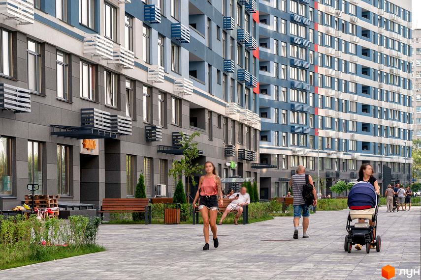 Зовнішній вигляд житлового комплексу Галактика з сірим та блакитним фасадом, численними вікнами та балконами. На прибудинковій території розташовані лавки та зелені насадження.