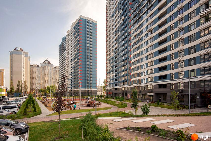 Житловий комплекс Галактика: висотні будинки з блакитно-білими фасадами та червоними акцентами. Доглянута прибудинкова територія з дитячим майданчиком та зонами відпочинку.