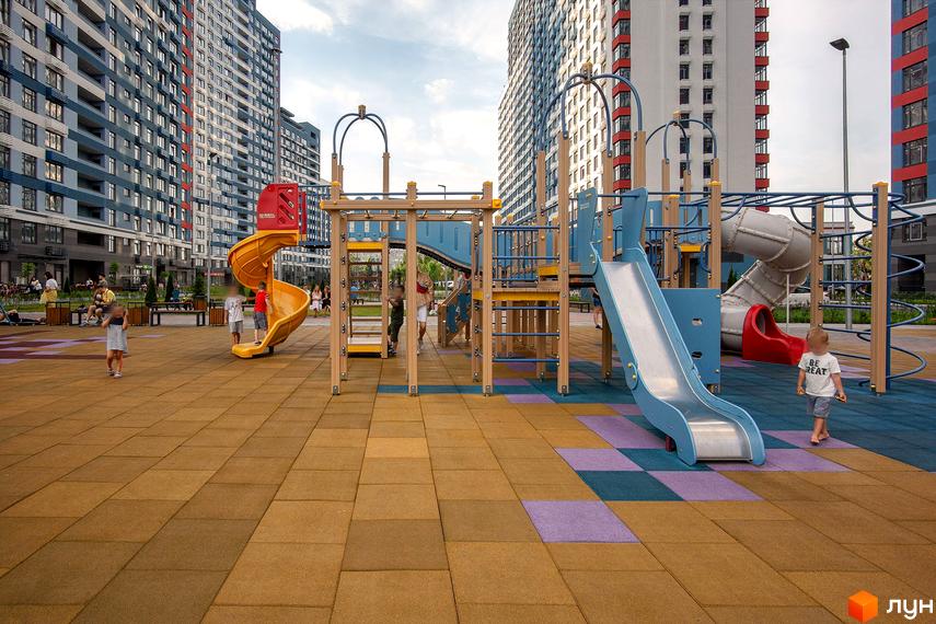 Житловий комплекс Галактика: дитячий майданчик з гірками та високі будинки. Територія комплексу для відпочинку та ігор дітей.