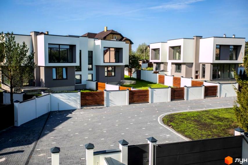 Котеджне містечко Riviera Gold: двоповерхові будинки з біло-сірими фасадами та великими вікнами, огороджені білими парканами з дерев'яними вставками.